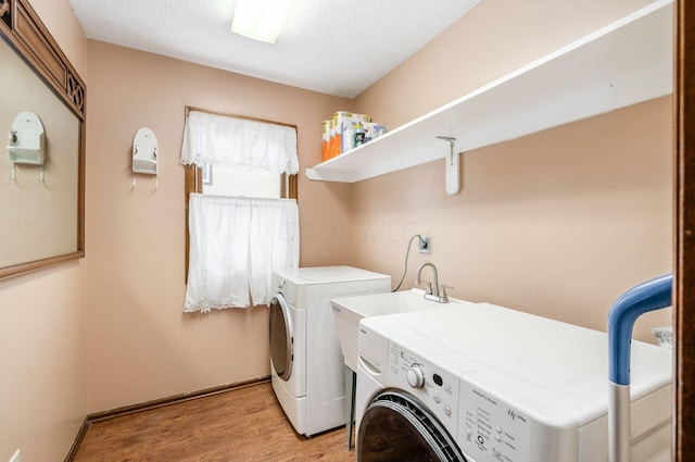 laundry room with washer and clothes dryer, light hardwood / wood-style floors, and a textured ceiling