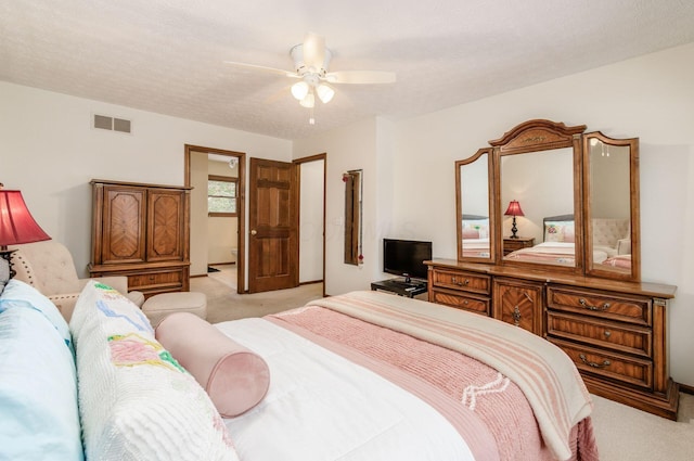 bedroom featuring ceiling fan, light carpet, and a textured ceiling