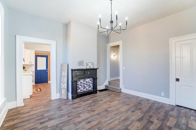 unfurnished living room featuring a notable chandelier and dark hardwood / wood-style flooring