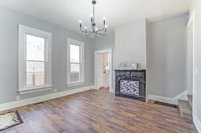 unfurnished living room featuring a healthy amount of sunlight, dark hardwood / wood-style flooring, and a chandelier