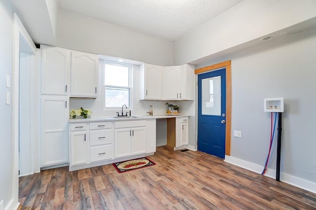 kitchen with white cabinets, a textured ceiling, sink, and dark wood-type flooring