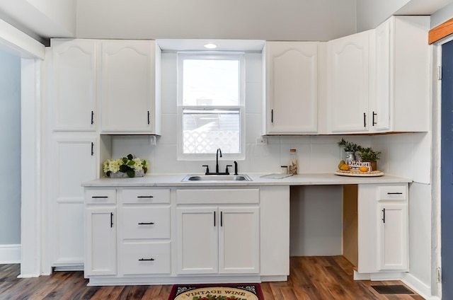 kitchen featuring dark hardwood / wood-style floors, decorative backsplash, white cabinetry, and sink