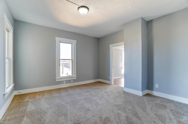 spare room with light carpet and a textured ceiling