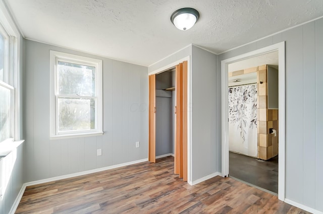 unfurnished bedroom featuring a closet, wood-type flooring, and a textured ceiling