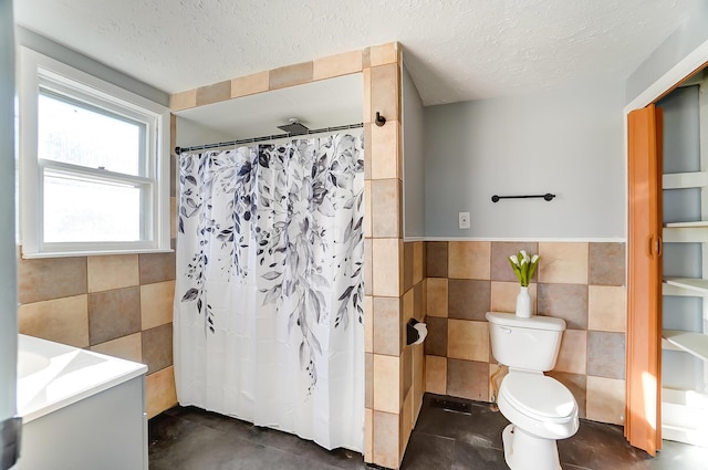 bathroom featuring a textured ceiling, toilet, vanity, tile walls, and a shower with shower curtain