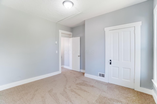 unfurnished bedroom with light carpet, a closet, and a textured ceiling