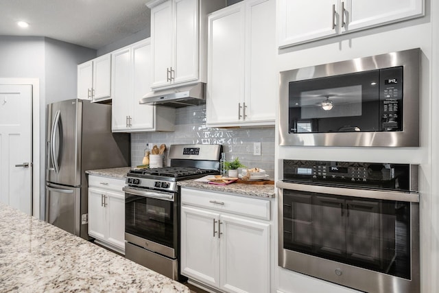 kitchen with white cabinetry, appliances with stainless steel finishes, light stone countertops, and backsplash