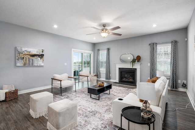 living room featuring ceiling fan, dark wood-type flooring, and a textured ceiling