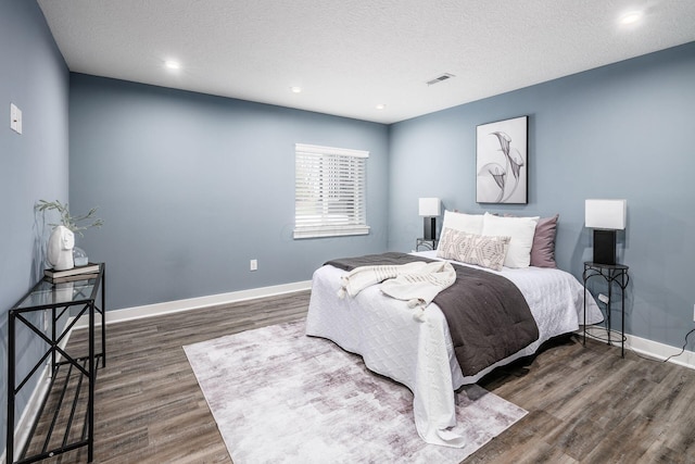 bedroom with dark hardwood / wood-style floors and a textured ceiling