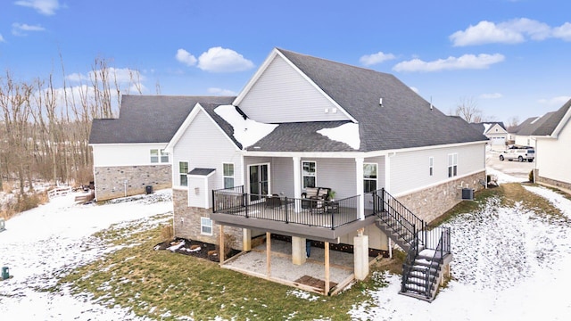 snow covered rear of property with a wooden deck