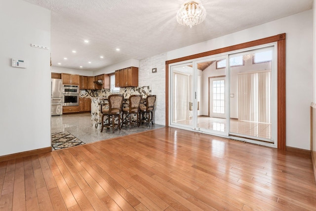 interior space with a textured ceiling, light wood-type flooring, and an inviting chandelier