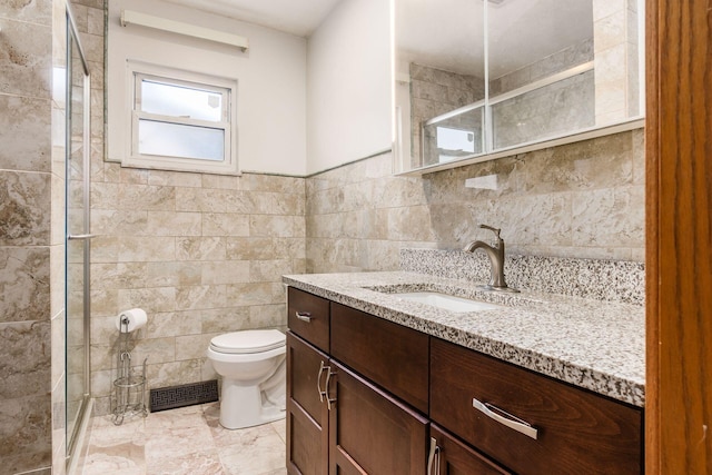 bathroom with tile walls, toilet, a shower with shower door, and vanity