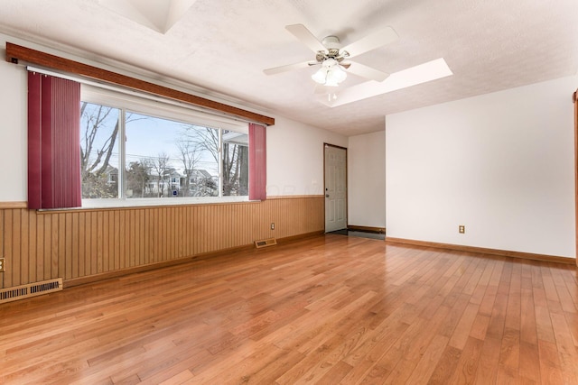 spare room with a textured ceiling, ceiling fan, and light hardwood / wood-style flooring