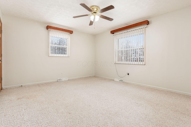 unfurnished room with a textured ceiling, carpet floors, ceiling fan, and plenty of natural light