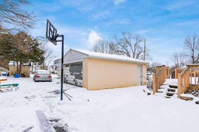 view of snowy exterior with a garage and an outbuilding