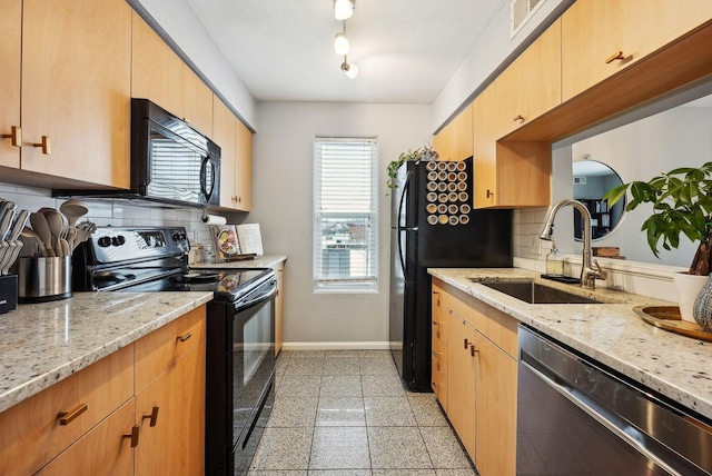 kitchen with backsplash, light stone counters, sink, and black appliances