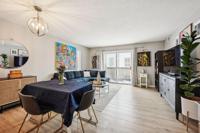 dining space featuring a textured ceiling, an inviting chandelier, and light hardwood / wood-style flooring