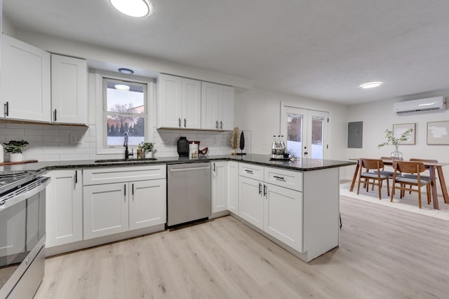 kitchen with kitchen peninsula, a wall unit AC, stainless steel appliances, white cabinetry, and sink