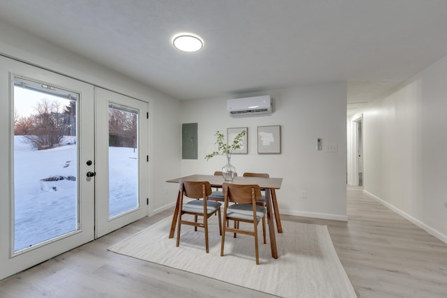 dining area with a wall unit AC, french doors, and light wood-type flooring