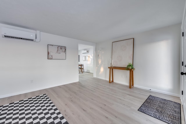 empty room featuring an AC wall unit and light hardwood / wood-style flooring