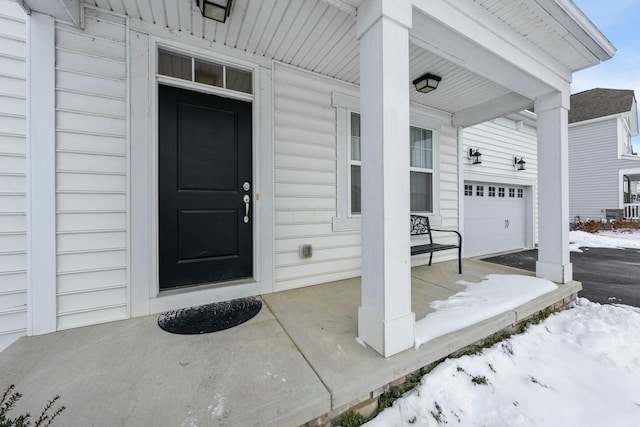 snow covered property entrance with a garage