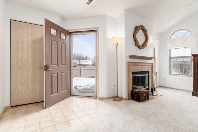 entryway featuring light colored carpet, a fireplace, a textured ceiling, and baseboards