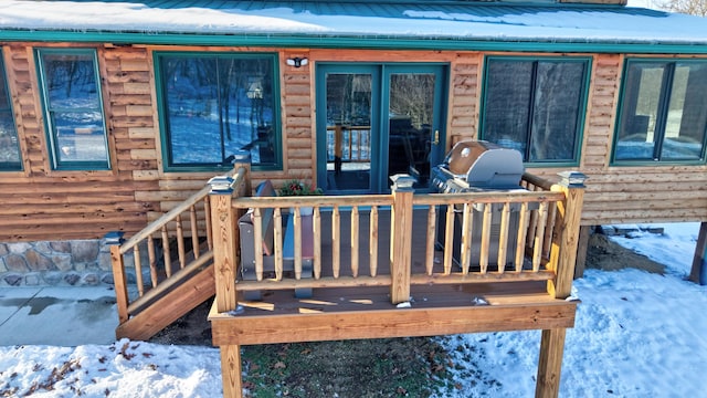 snow covered property entrance featuring a deck