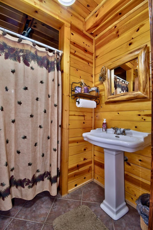 bathroom with tile patterned floors and wooden walls