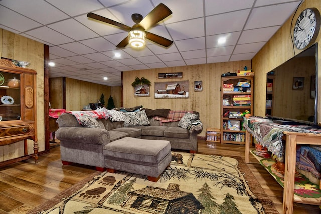 living room featuring dark hardwood / wood-style flooring, ceiling fan, and wooden walls