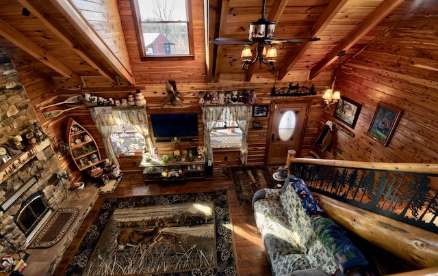 living room featuring wooden ceiling, a stone fireplace, wooden walls, ceiling fan, and beamed ceiling