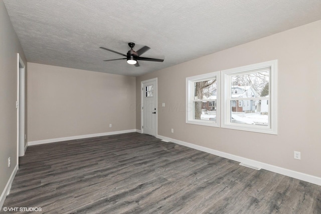 empty room with a textured ceiling, ceiling fan, and dark hardwood / wood-style floors