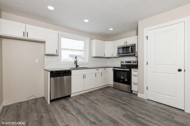 kitchen with backsplash, stainless steel appliances, white cabinetry, and sink