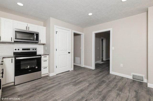 kitchen featuring dark wood-type flooring, white cabinets, stainless steel appliances, and a textured ceiling