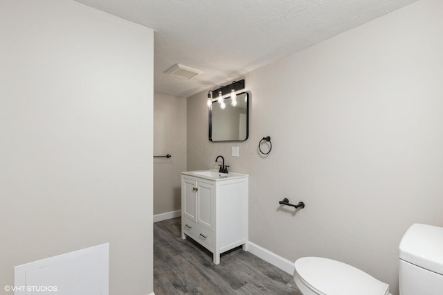 bathroom with vanity, toilet, wood-type flooring, and a textured ceiling