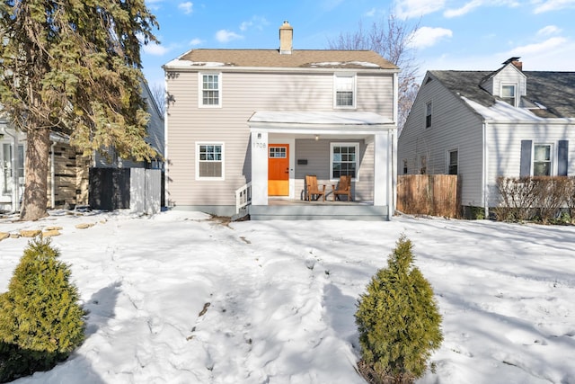 snow covered back of property featuring covered porch