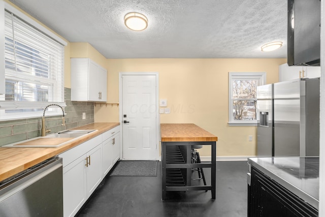 kitchen with decorative backsplash, appliances with stainless steel finishes, white cabinetry, and sink