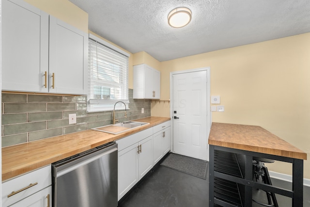 kitchen featuring wood counters, backsplash, sink, stainless steel dishwasher, and white cabinetry