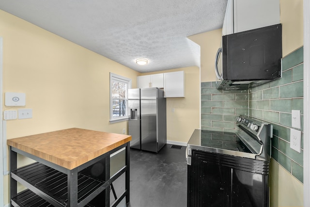 kitchen featuring backsplash, white cabinetry, stainless steel appliances, and a textured ceiling