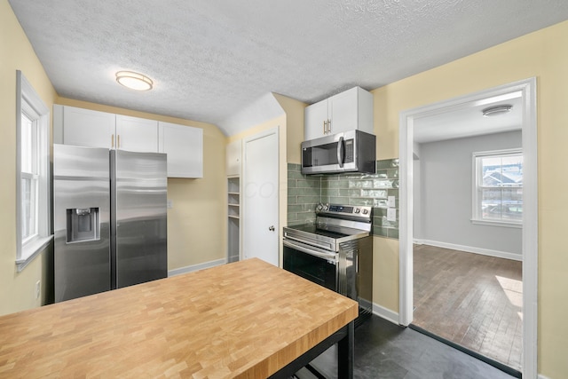 kitchen with backsplash, white cabinets, a textured ceiling, and appliances with stainless steel finishes