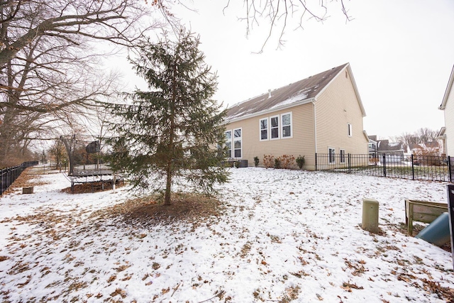 snow covered back of property featuring a trampoline