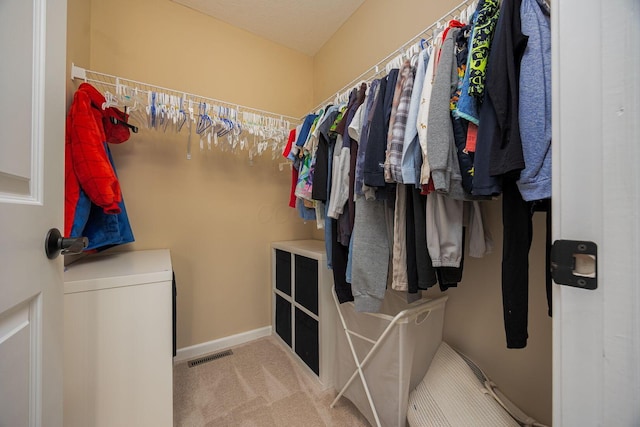 walk in closet featuring light carpet