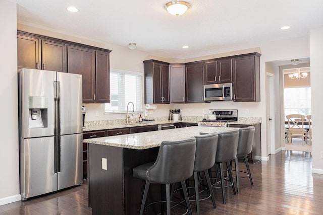 kitchen with stainless steel appliances, dark hardwood / wood-style floors, a kitchen island, and plenty of natural light