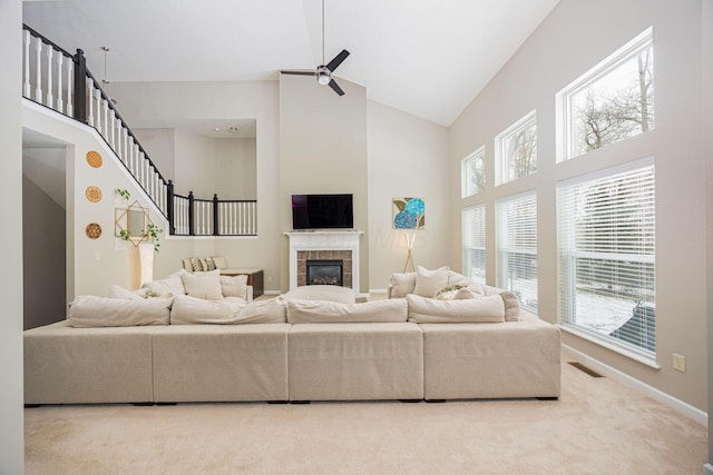 living room featuring a tiled fireplace, ceiling fan, carpet flooring, and high vaulted ceiling