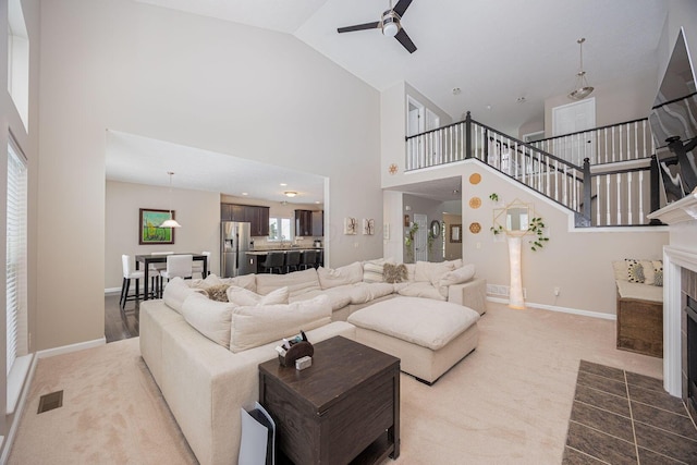 living room featuring a fireplace, high vaulted ceiling, and ceiling fan