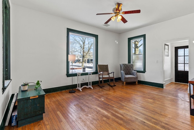 living area featuring wood-type flooring, ceiling fan, and a baseboard heating unit