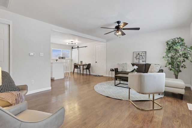 living room with ceiling fan, a barn door, and hardwood / wood-style floors