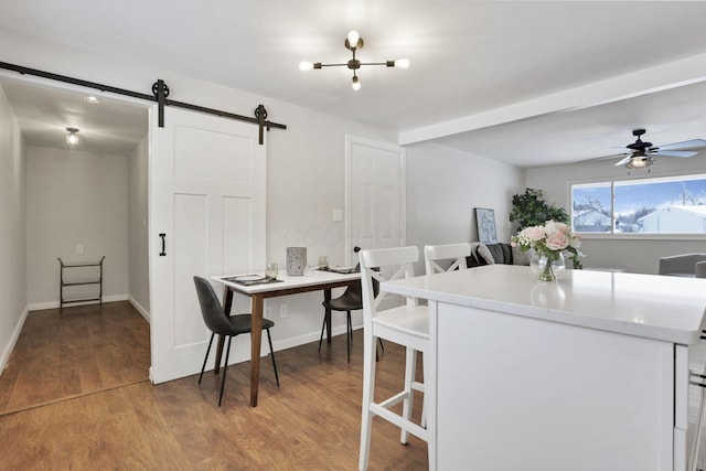 dining room featuring ceiling fan, a barn door, and wood-type flooring