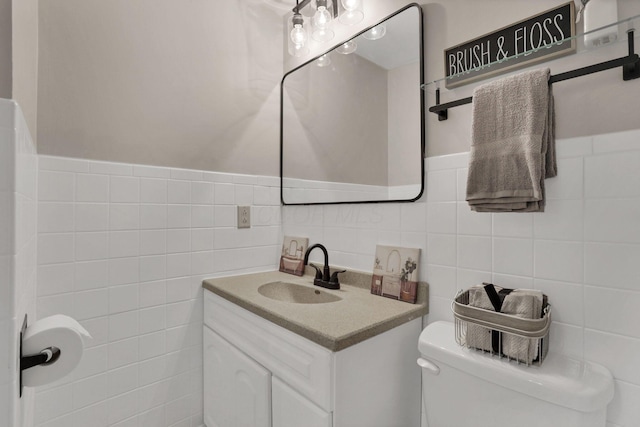 bathroom featuring toilet, vanity, and tile walls