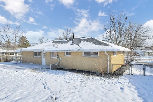 snow covered back of property featuring cooling unit