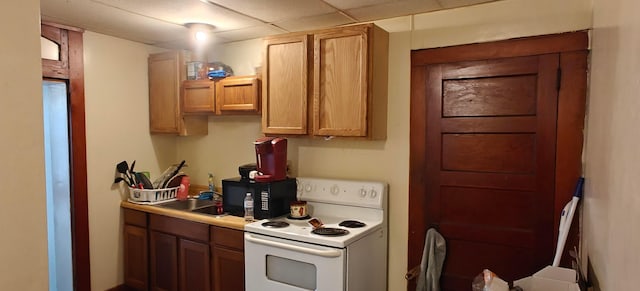 kitchen with a drop ceiling, white electric range oven, and sink